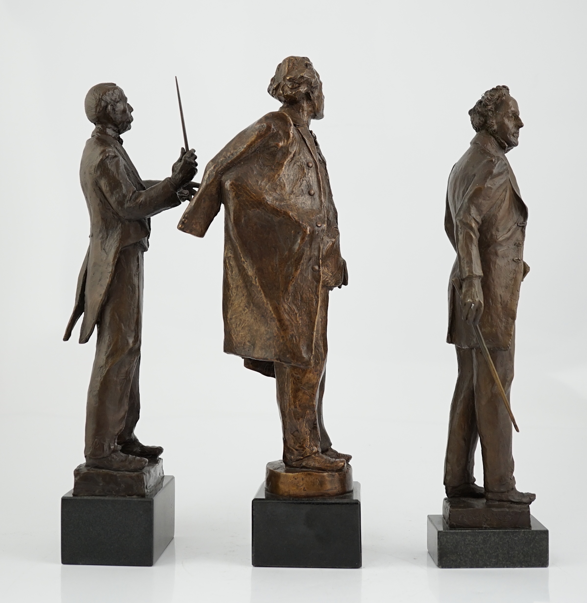 Anthony Hawken FRSS (British, b.1948), three bronze figures of composers, Gustav Mahler, Sir Edward Elgar and Mendelssohn, one standing holding a baton aloft, one standing carrying a baton and volume, the third with coat